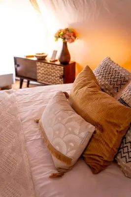 a bed with two pillows and a vase of flowers at Glamping Gozdna Jasa in Bovec