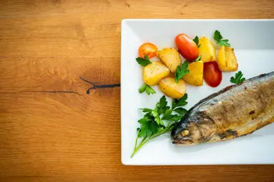 a plate with a fish and vegetables on a table at Penzion Šterk in Most na Soči