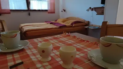 a table with two cups and plates on a table with a bed at Apartments Bobi in Tolmin