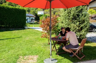 two people sitting at a table under an umbrella at Apartments Bobi in Tolmin