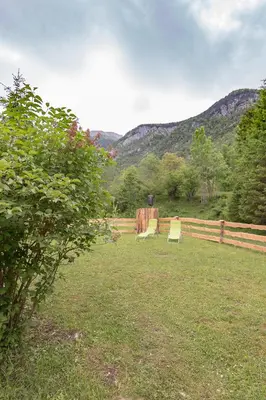 two chairs in a yard with mountains in the background at Lizina hiška House Bohinj in Bohinjska Bistrica