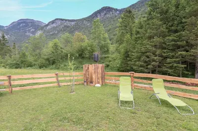 two chairs sitting in the grass in front of a fence at Lizina hiška House Bohinj in Bohinjska Bistrica