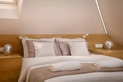 a bedroom with a large bed with white and pink pillows at Vila Emona - Central Apartments - Free Parking in Ljubljana
