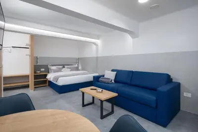 a living room with a blue couch and a bed at Vila Emona - Central Apartments - Free Parking in Ljubljana