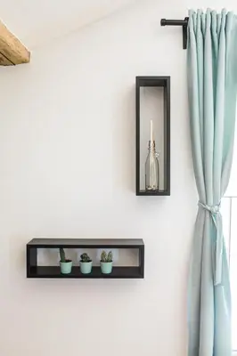 a shelf on a wall with two plants and a mirror at Štulceva Hiša in Most na Soči
