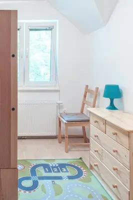 a bedroom with a chair and a dresser with a rug at Villa Melody in Bohinj