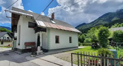 a small white house with mountains in the background at Apartma Majda in Kranjska Gora