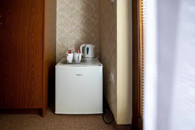 a small white refrigerator sitting in a room at Sobe Ličef in Bohinj