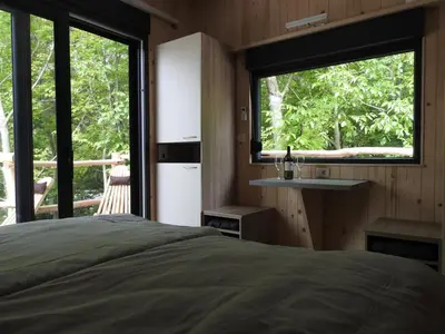 a bedroom with a bed and a large window at Počitniški hišici - Small holiday houses in Ajdovščina