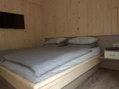 a bed in a room with a tv on a wall at Počitniški hišici - Small holiday houses in Ajdovščina