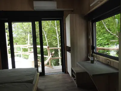 a bedroom with a bed and a sliding glass door at Počitniški hišici - Small holiday houses in Ajdovščina