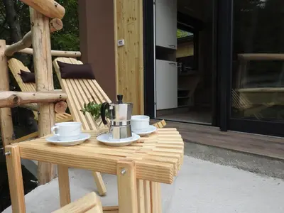 a coffee maker sitting on a wooden table on a porch at Počitniški hišici - Small holiday houses in Ajdovščina