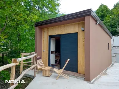 a tiny house with a porch and two chairs at Počitniški hišici - Small holiday houses in Ajdovščina