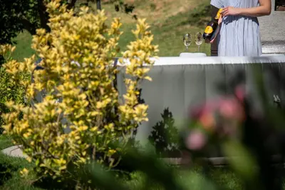 a woman standing next to a table with wine glasses at Martin's Family Cottage with Hot Tub & Views in Šmarje pri Jelšah