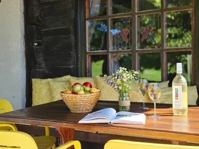 a table with a basket of fruit and a bottle of wine at Martin's Family Cottage with Hot Tub & Views in Šmarje pri Jelšah