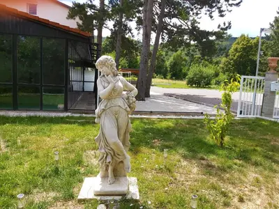 a statue of a woman sitting in the grass at Divača, Vila Srebrna in Divača