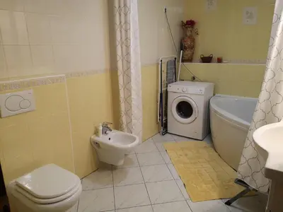 a bathroom with a toilet a sink and a washing machine at Apartma Juteršek in Libeliče