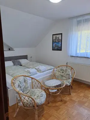 a bedroom with a bed and two chairs and a table at Apartma Juteršek in Libeliče