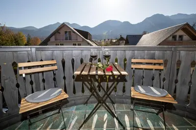 a table with two chairs and wine glasses on a balcony at Bohinj - Apartment Ana in Bohinj