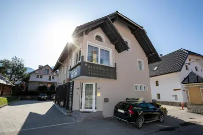 a black car parked in front of a white house at Bohinj - Apartment Ana in Bohinj