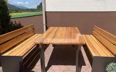 a wooden table sitting next to two benches at Hiša MIHA Stunning Spacious House & Apartment Podkoren Kranjska Gora in Kranjska Gora