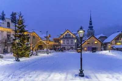 a street light in a snow covered town at night at Hiša MIHA Stunning Spacious House & Apartment Podkoren Kranjska Gora in Kranjska Gora