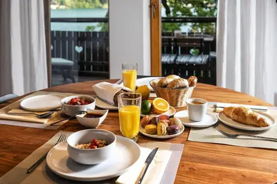 a wooden table with breakfast foods and drinks on it at Private beach house on Lake Bled in Bled