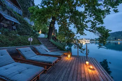 a wooden deck with lounge chairs and a body of water at Private beach house on Lake Bled in Bled