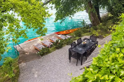 a table and chairs and a boat on the water at Private beach house on Lake Bled in Bled