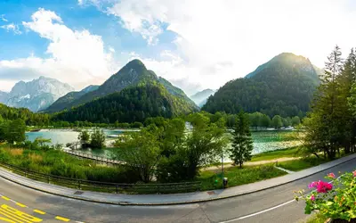a winding road next to a river and mountains at House Moose't Getaway, Kranjska Gora in Kranjska Gora