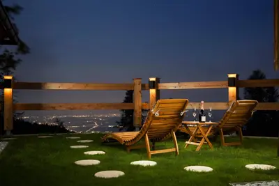 two chairs and a table with wine bottles on the grass at Luxury Alpine Chalet & Sauna Pinja - Velika Planina - I FEEL ALPS in Stahovica
