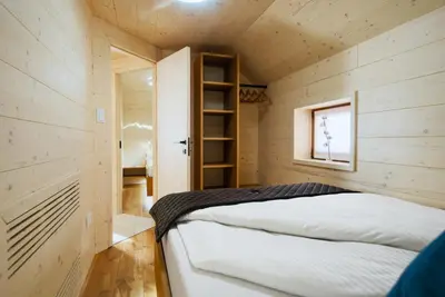 a small bedroom with a bed in a wooden cabin at Luxury Alpine Chalet & Sauna Pinja - Velika Planina - I FEEL ALPS in Stahovica