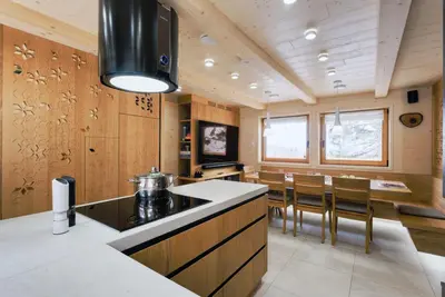 a kitchen with wooden walls and a kitchen island with chairs at Luxury Alpine Chalet & Sauna Pinja - Velika Planina - I FEEL ALPS in Stahovica