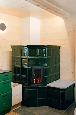 a fireplace in a room with a green tile wall at Chalet Lepenatka with Sauna - I feel Alps in Stahovica