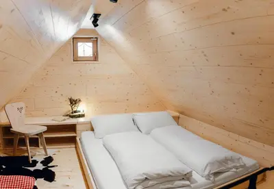 a white bed in a wooden room with a table at Chalet Lepenatka with Sauna - I feel Alps in Stahovica