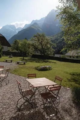 a picnic table and chairs with mountains in the background at Gorska Roža in Log pod Mangartom