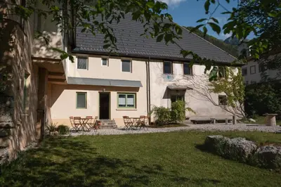 a white house with tables and chairs in a yard at Gorska Roža in Log pod Mangartom