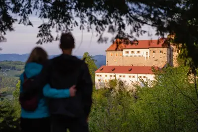 a man and a woman standing in front of a castle at Rooms & Apartments Podsreda Castle in Podsreda