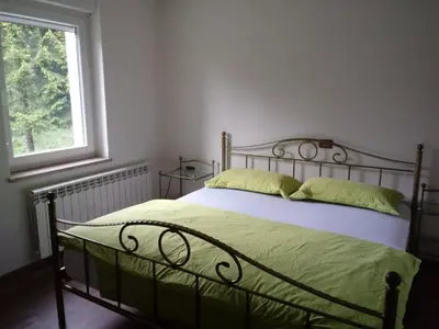 a bedroom with a bed with green sheets and a window at Apartmaji Velikonja in Ajdovščina