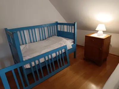 a blue crib in a room with a lamp and a table at Country House Pri Lipet Žiri in Žiri