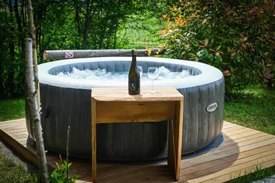 a barrel hot tub with a bottle of wine and a glass at Hut at the forest in Male Brusnice