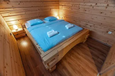 a bed in a wooden cabin with blue sheets and pillows at Log House Natura in Radovljica