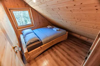 a small bed in a wooden room with a window at Log House Natura in Radovljica