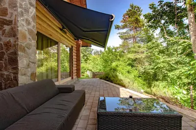 a living room with a couch and a glass table at Log House Natura in Radovljica