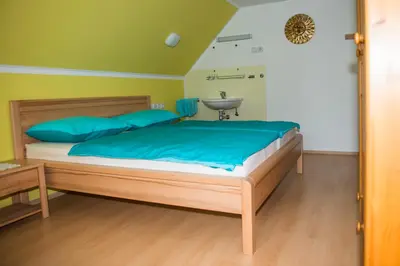 a bedroom with a bed with blue pillows and a sink at Apartma Košnik PERUNIKA in Bohinj