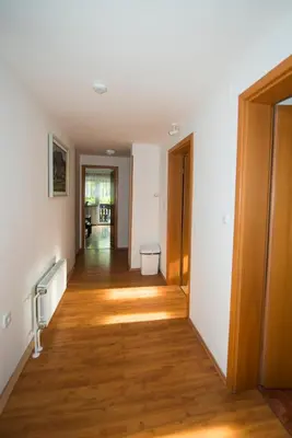 a hallway of an apartment with wooden floors and white walls at Apartma Košnik PERUNIKA in Bohinj