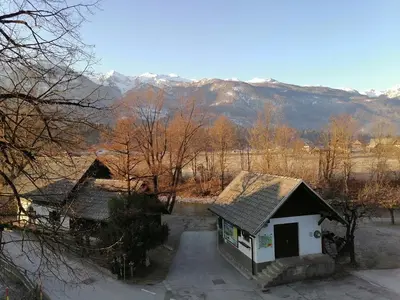 a small house with a mountain in the background at Apartma Košnik PERUNIKA in Bohinj