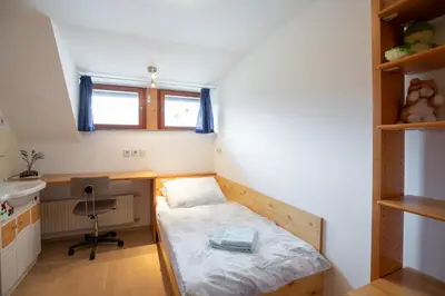 a small room with a bed and a desk at Apartma Košnik PERUNIKA in Bohinj