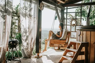 a woman sitting in a porch swing looking out a window at Zidanica Lackner in Črnomelj