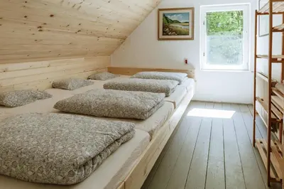 four beds lined up in a room with a window at Dom na Slivnici in Cerknica